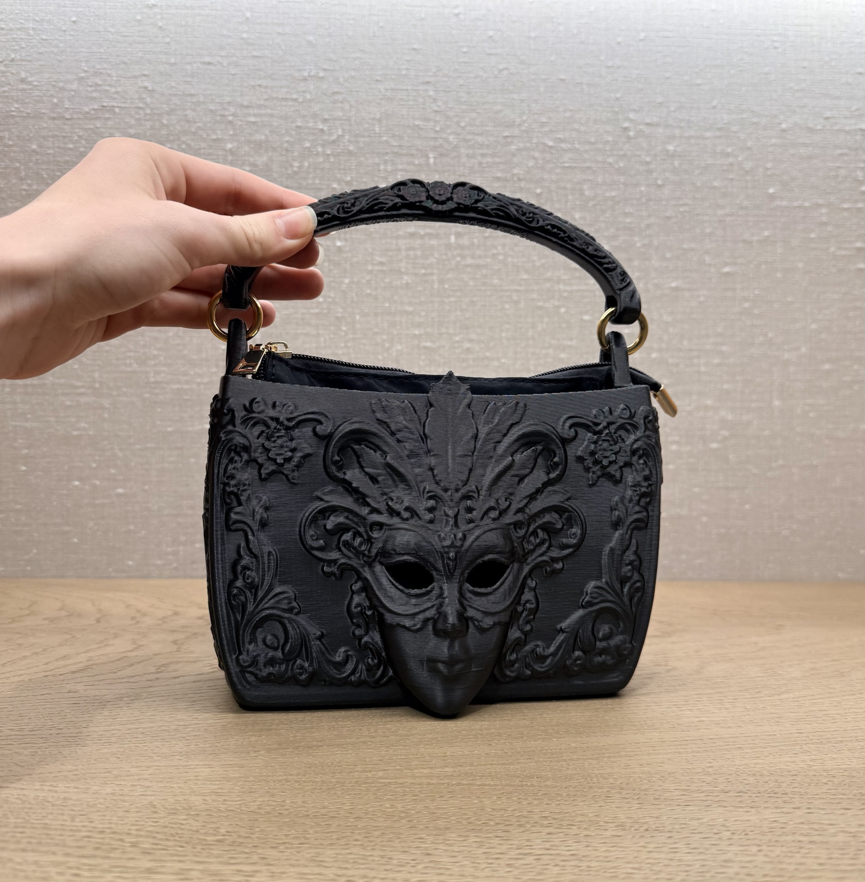 Black sculptural bag with a carnival mask relief